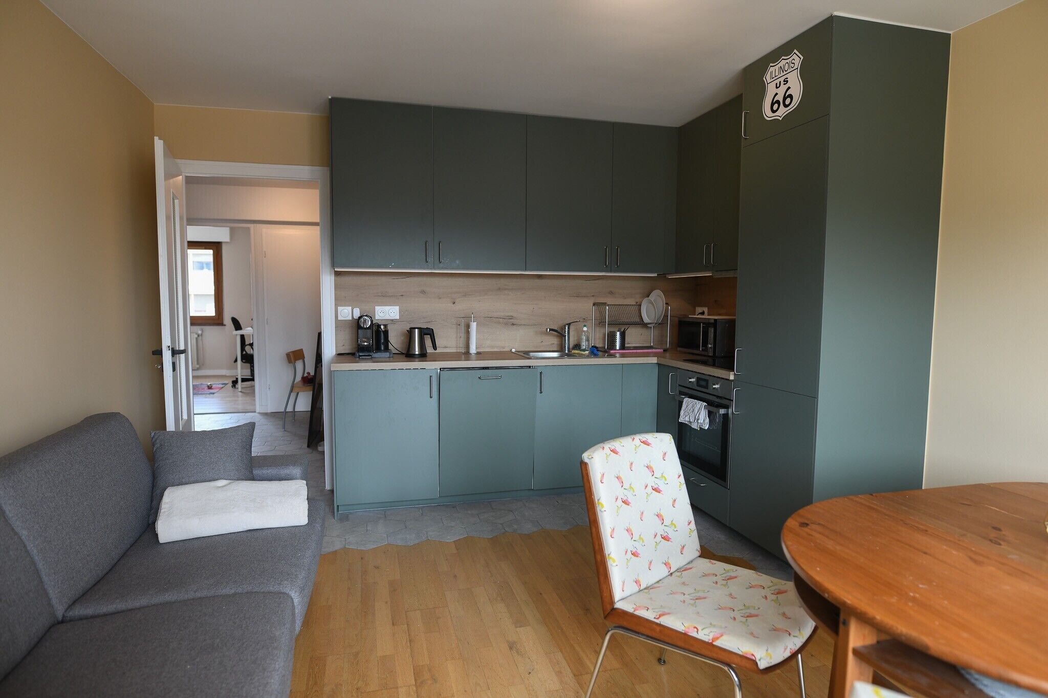 A compact living space with a kitchenette, a sofa, a chair, and a dining table.