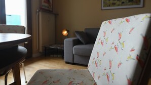 Una sala de estar con un sofá, una mesa de comedor y una silla con estampado de pájaros.