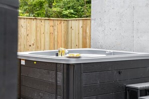 A hot tub with a wooden deck and a concrete wall in the background. - Gatlinburg Luxury Cabin: Hot Tub, Arcade, Accessible Suite, Treehouse Vibe (Gatlinburg)