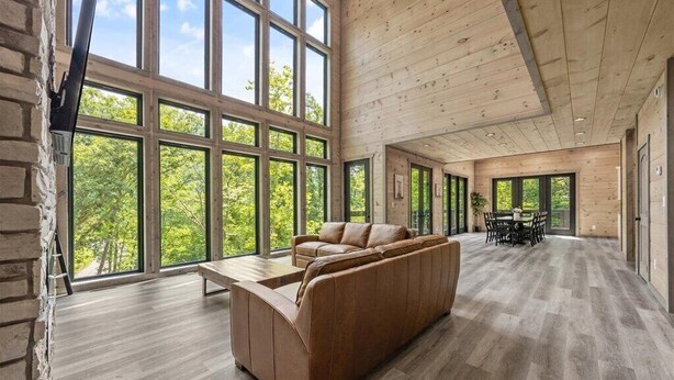 A spacious room with a large window, a sofa, and a dining area.