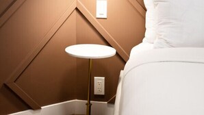 A bedroom with a bed, a white pillow, a wall-mounted lamp, and a floor lamp.