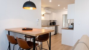 A modern kitchen with a wooden island, bar stools, and a pendant light.