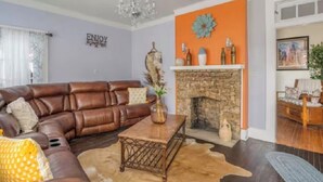 A living room with a leather sofa, a coffee table, a fireplace, and a chandelier.