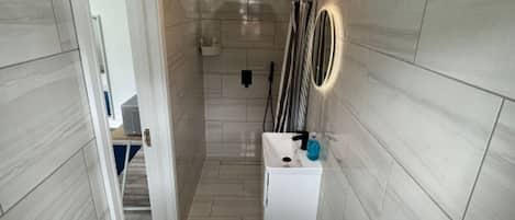 Een douche, een bidet, handdoeken, toiletpapier