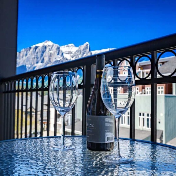 A table with two wine glasses and a bottle of wine, set against a mountain backdrop.