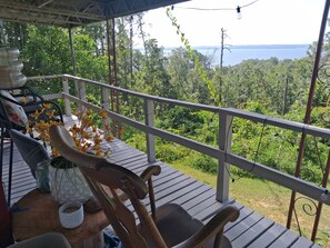 A wooden deck with a railing, chairs, and a table with a vase of flowers.