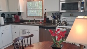 Una cocina con armarios blancos, horno de acero inoxidable, microondas y una mesa de comedor con sillas.