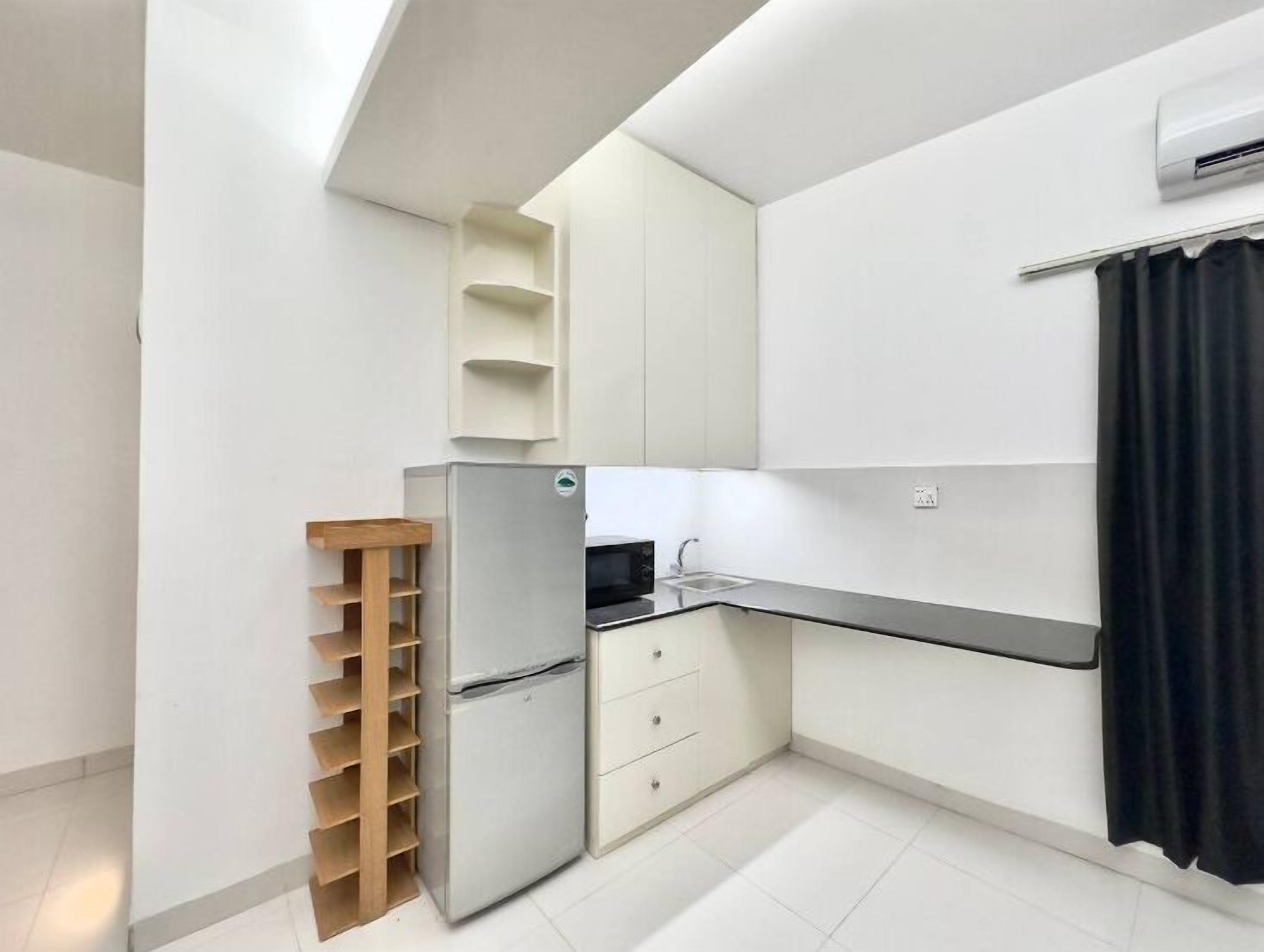 A compact kitchen with a built-in refrigerator, a sink, and a wooden rack.