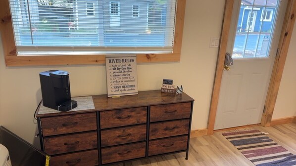 A wooden dresser with a sign titled "RIVER RULES" listing activities like taking a beat ride and relaxing by the fire. - NEWLY RENOVATED! Cozy cabin in peaceful Oscoda with WiFi, AC (Oscoda)