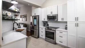 A modern kitchen with white cabinets, stainless steel appliances, and a built-in oven.