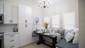 A modern kitchen with white cabinets, a dining table set with plates, and a chandelier.