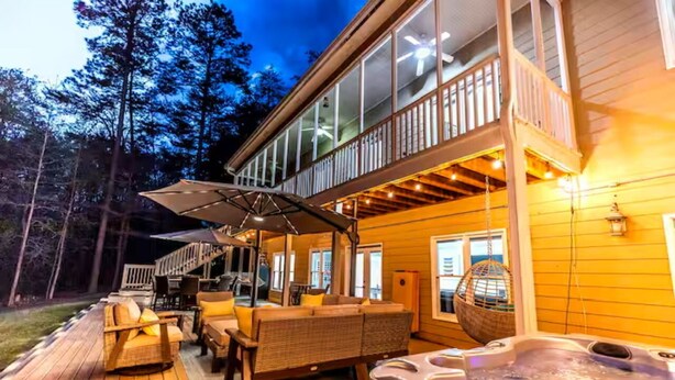 A wooden deck with outdoor furniture, a hot tub, and a covered seating area.