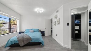 Un dormitorio moderno con cama, armario y ventana.