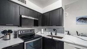 Una cocina moderna con armarios de madera oscura, electrodomésticos de acero inoxidable y encimera blanca.