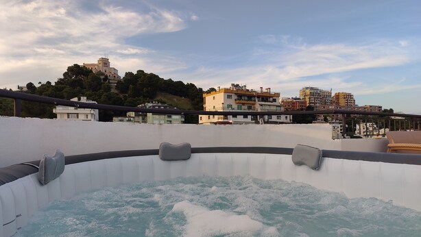 Uma banheira de hidromassagem com vista para prédios e uma colina ao fundo.