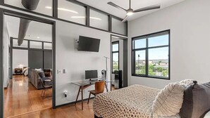 A modern bedroom with a large bed, a desk, and a television.