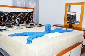 Een bed met een witte deken, een blauwe handdoek en een houten hoofdbord.