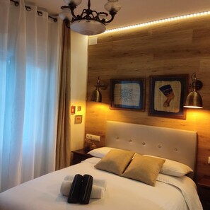 A hotel room with a bed, a wooden headboard, a nightstand, and a wall-mounted lamp. - House with 9 private rooms (Barcelona)