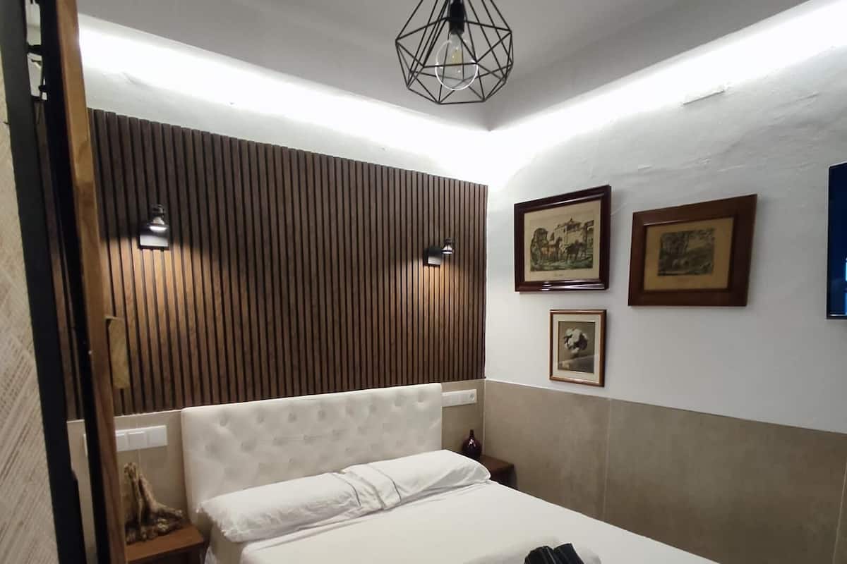 Una habitación de hotel con una cama, un panel de pared de madera y fotografías enmarcadas.