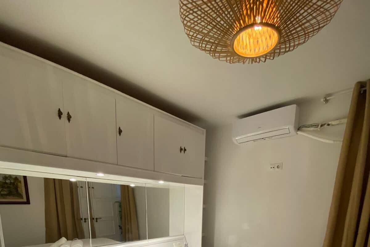 Una habitación de hotel con cama, mesita de noche, cómoda, espejo y lámpara colgante.