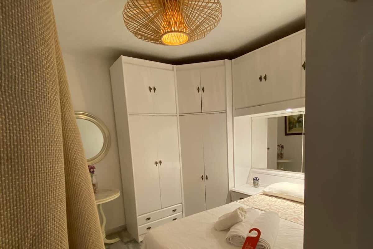 Un dormitorio con cama, armario blanco y lámpara colgante.