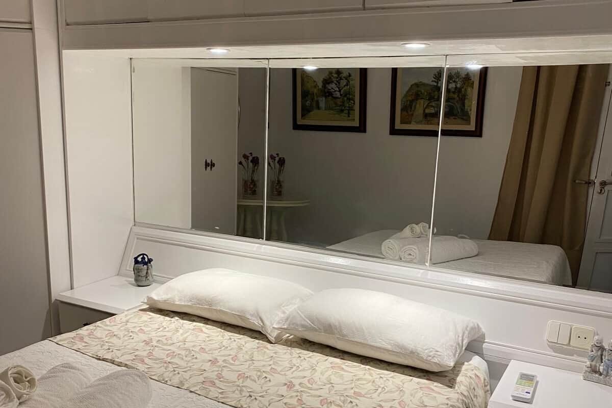 Un dormitorio con una cama grande, una mesita de noche, un espejo y un armario.