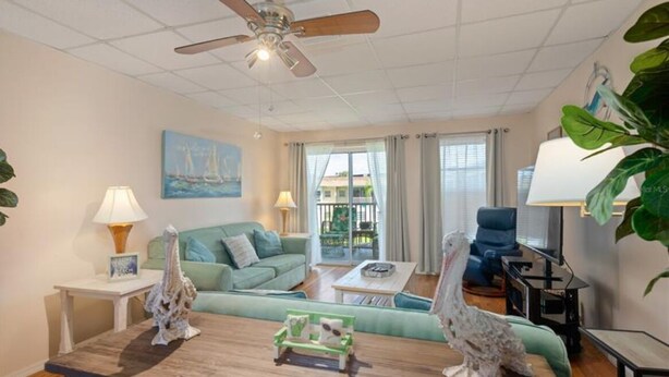 A living room with a ceiling fan, a green sofa, a coffee table, and two decorative sculptures.