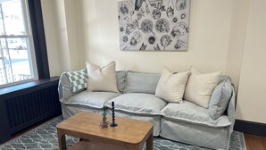 Ein Wohnzimmer mit grauem Sofa, einem Holztisch und einem gemusterten Teppich.