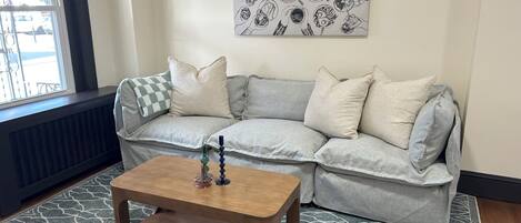 A living room with a grey sofa, a wooden coffee table, and a patterned rug.