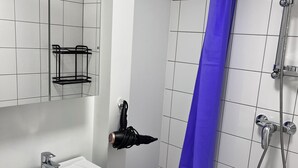 Een moderne badkamer met een wit wastafelmeubel, spiegel en douche.