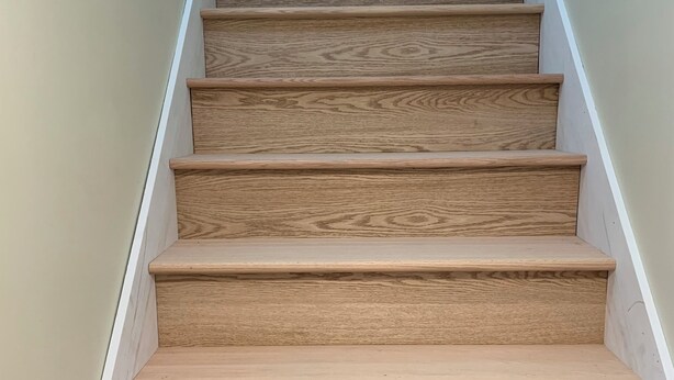 Una escalera de madera con barandilla blanca y paredes color crema.