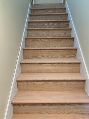 A wooden staircase with a white handrail and beige walls.