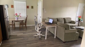 Una sala de estar con una mesa de comedor, un sofá y una computadora portátil sobre una mesita.