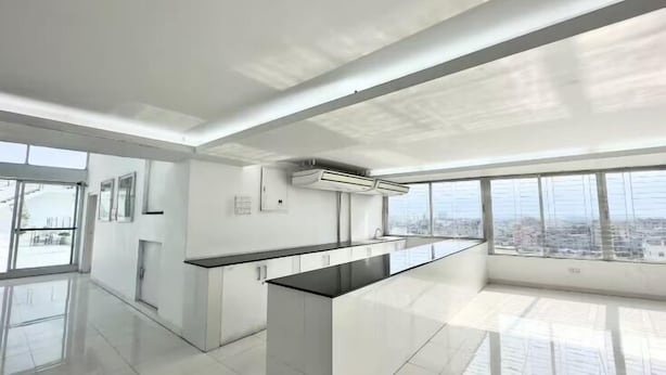 Une cuisine moderne dotée d’un îlot central, de grandes fenêtres et offrant une vue sur la ville.
