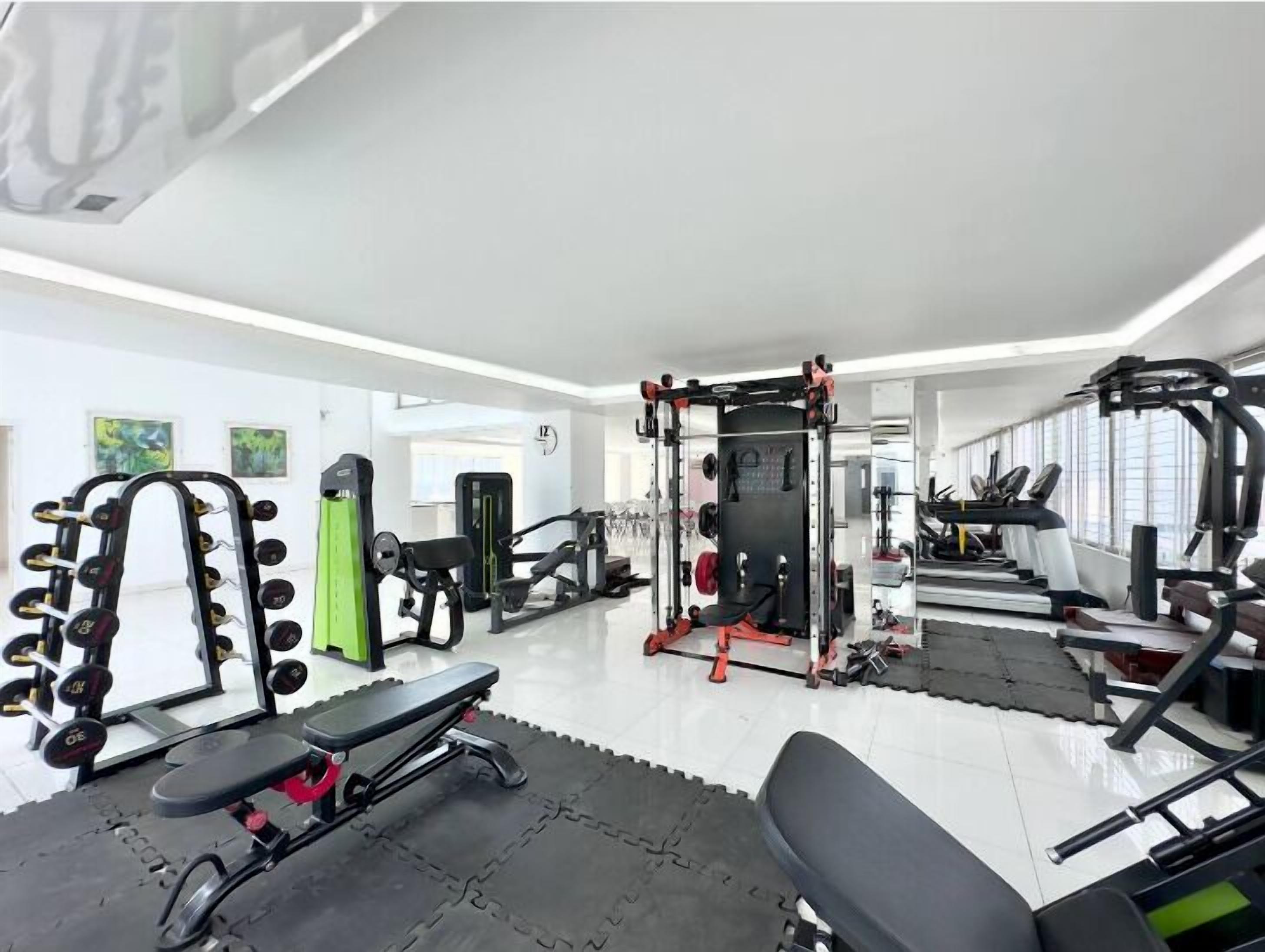 A gym with various exercise equipment, including dumbbells, a bench, and a squat rack.