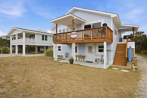 A two-story house with a balcony, a wooden deck, and a small porch area.