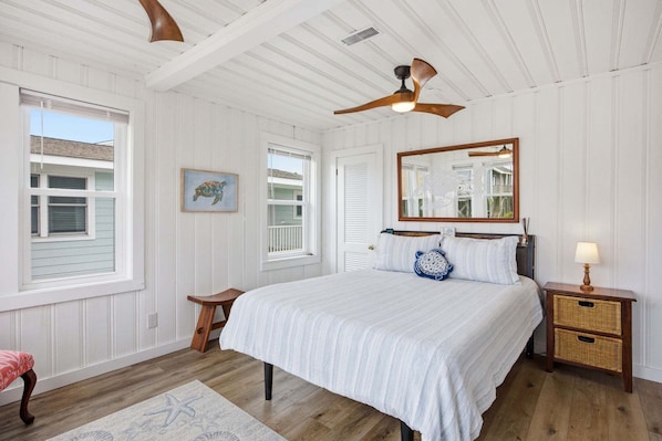A bedroom with a bed, a nightstand, a ceiling fan, and a window.