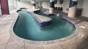 An indoor swimming pool with multiple lanes, a changing room area, and a seating section.