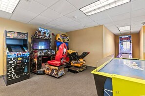 Een speelhal met verschillende spelautomaten, waaronder een racegame en een tafeltennistafel.