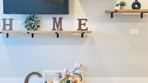 A room with a mounted TV, a 'HOME' sign, a decorative horse sculpture, and a Louis Vuitton box on a table.