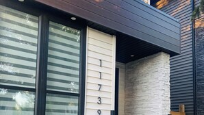 A modern house with a beige exterior, black-framed windows, and a stone accent wall.