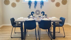 A dining area with a rectangular table set for four, surrounded by black chairs.