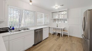 A modern kitchen with white cabinetry, a stainless steel refrigerator, and a built-in dishwasher. - Stripside Serenity –  4B3B Family Retreat, 5 mins from the strip (Las Vegas)