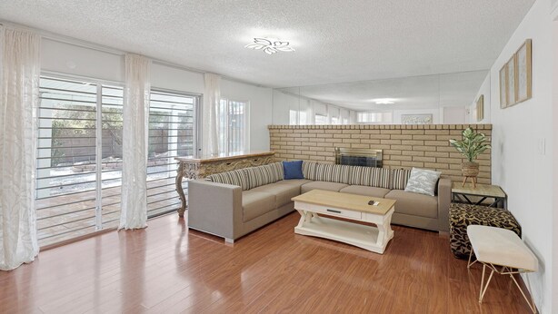 A spacious living room with a beige sofa, a wooden coffee table, and a brick accent wall. - Stripside Serenity –  4B3B Family Retreat, 5 mins from the strip (Las Vegas)