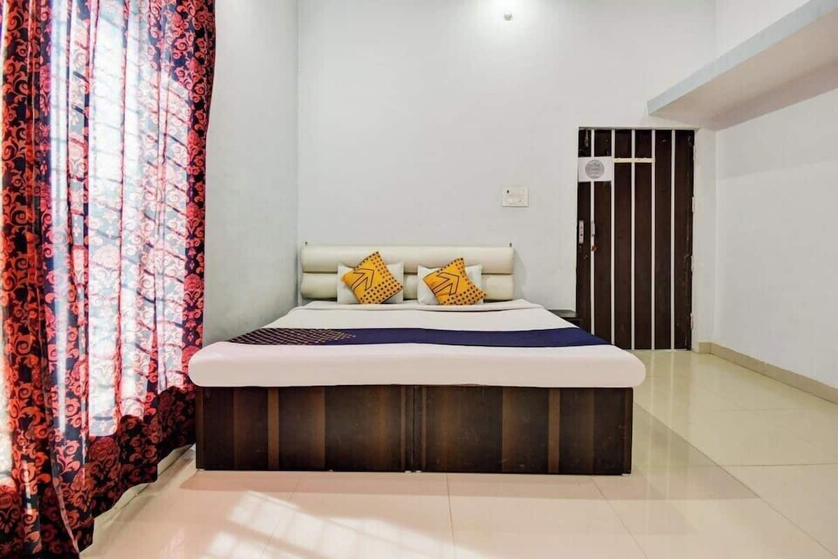 A bedroom with a bed, curtains, a door, and a light switch on the wall.