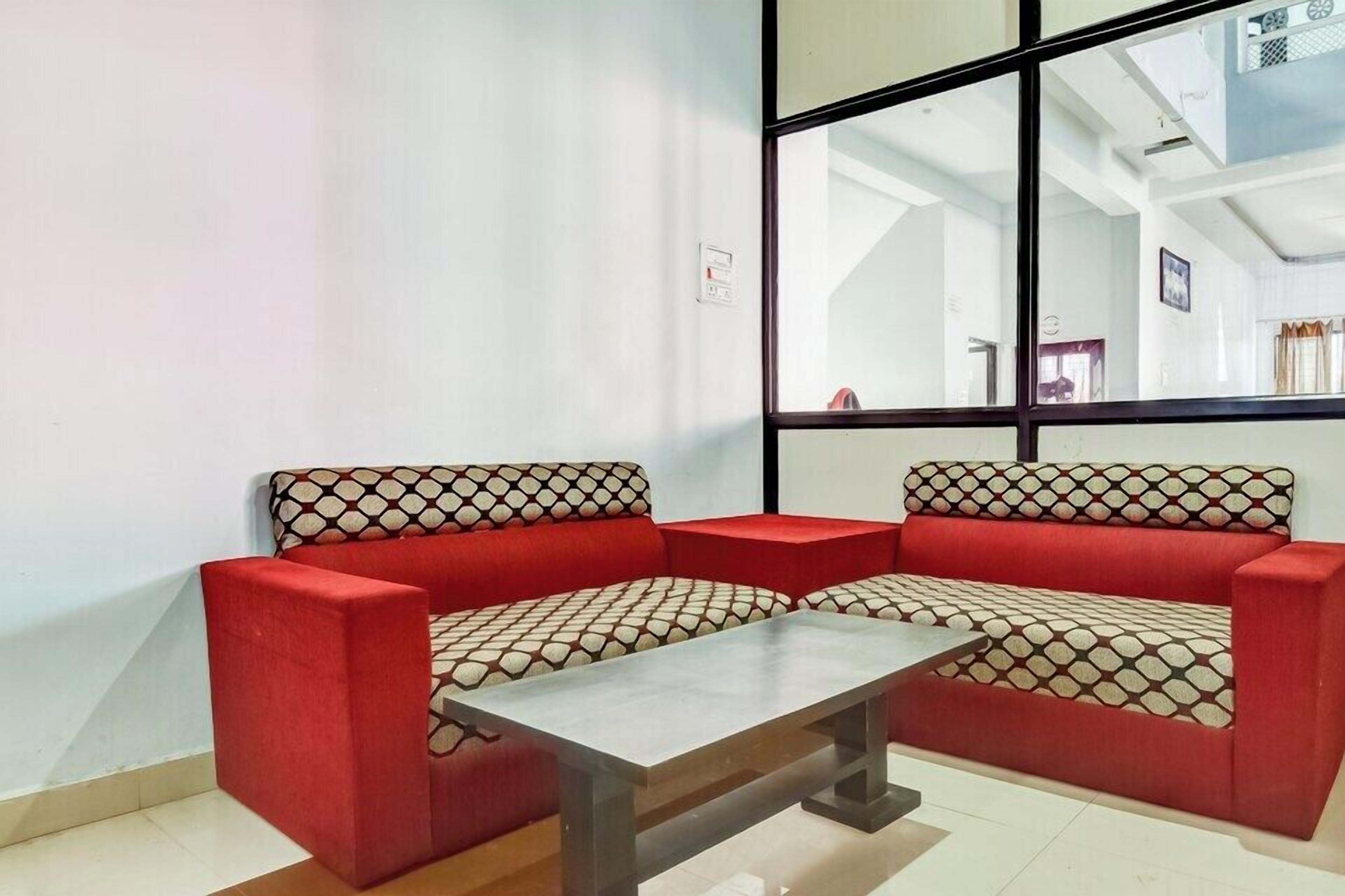 Un sofá rojo con cojines estampados, una mesita y un ventanal con vistas al interior.