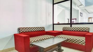 Un sofá rojo con cojines estampados, una mesita y un ventanal con vistas al interior.