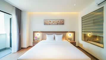 A hotel room with a large bed, bedside tables with lamps, a painting on the wall, and a large window.