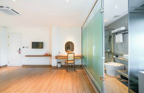 A modern bathroom with a shower, toilet, and sink. There is a wooden desk with a chair and a mirror. - Kien Ocean Hotel (Da Nang Municipality)