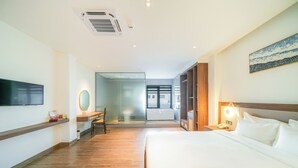 Hotellihuone, jossa on sänky, työpöytä, tuoli, televisio ja ikkuna.